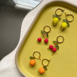 Cherry Hoop Earrings | Love Kiki | An array of fruit earrings on a yellow tray