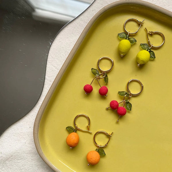 Lemon Hoop Earrings | Love Kiki | An assortment of fruit earrings on a yellow tray